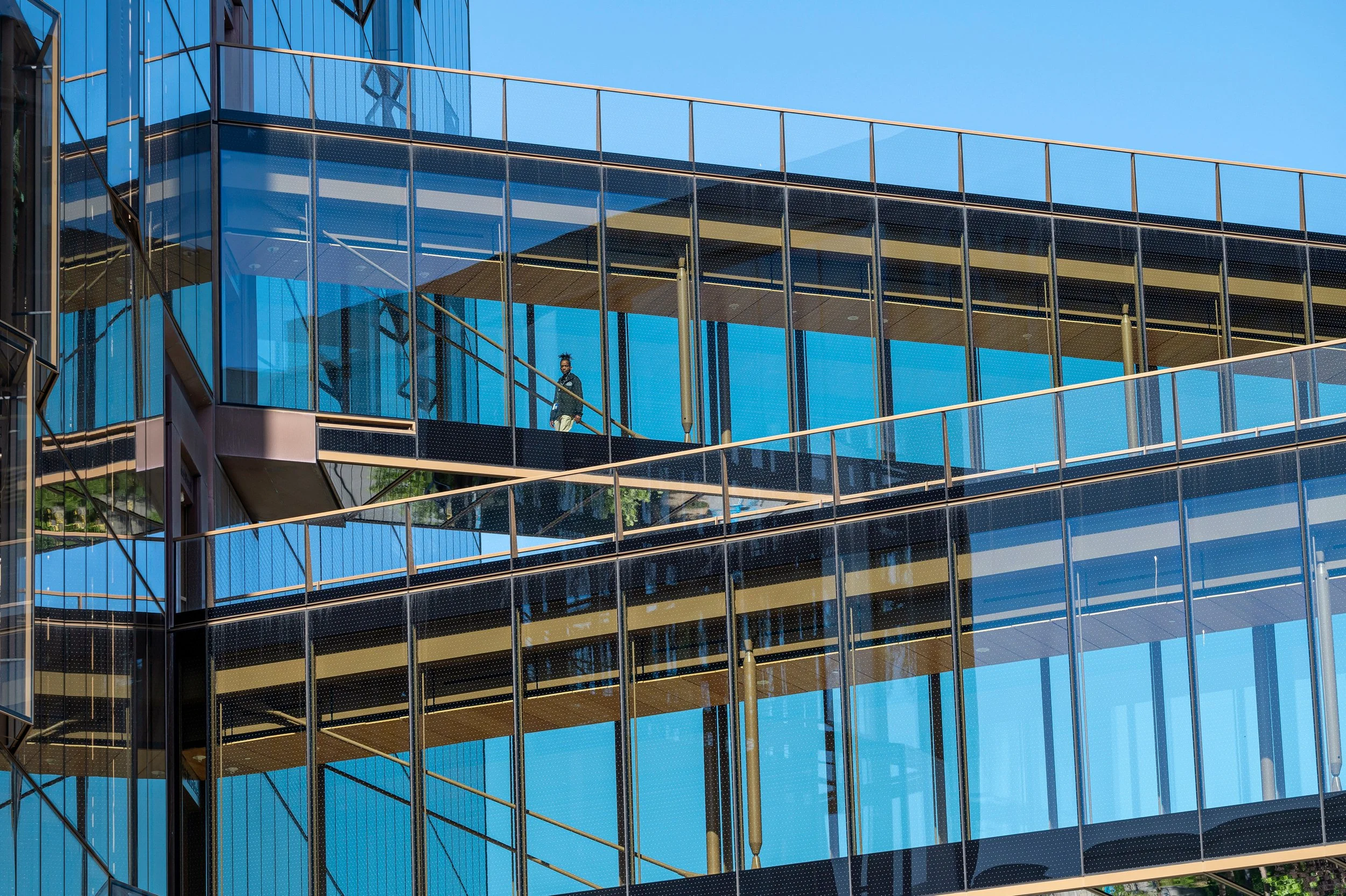 A person walks along a glass gangway in an office building