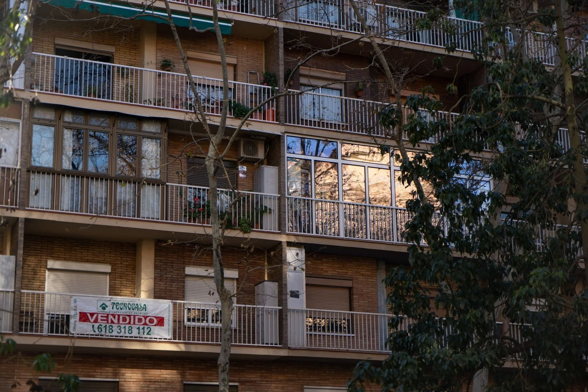 A banner reading "Sold" on the balcony of a residential building in Barcelona, Spain