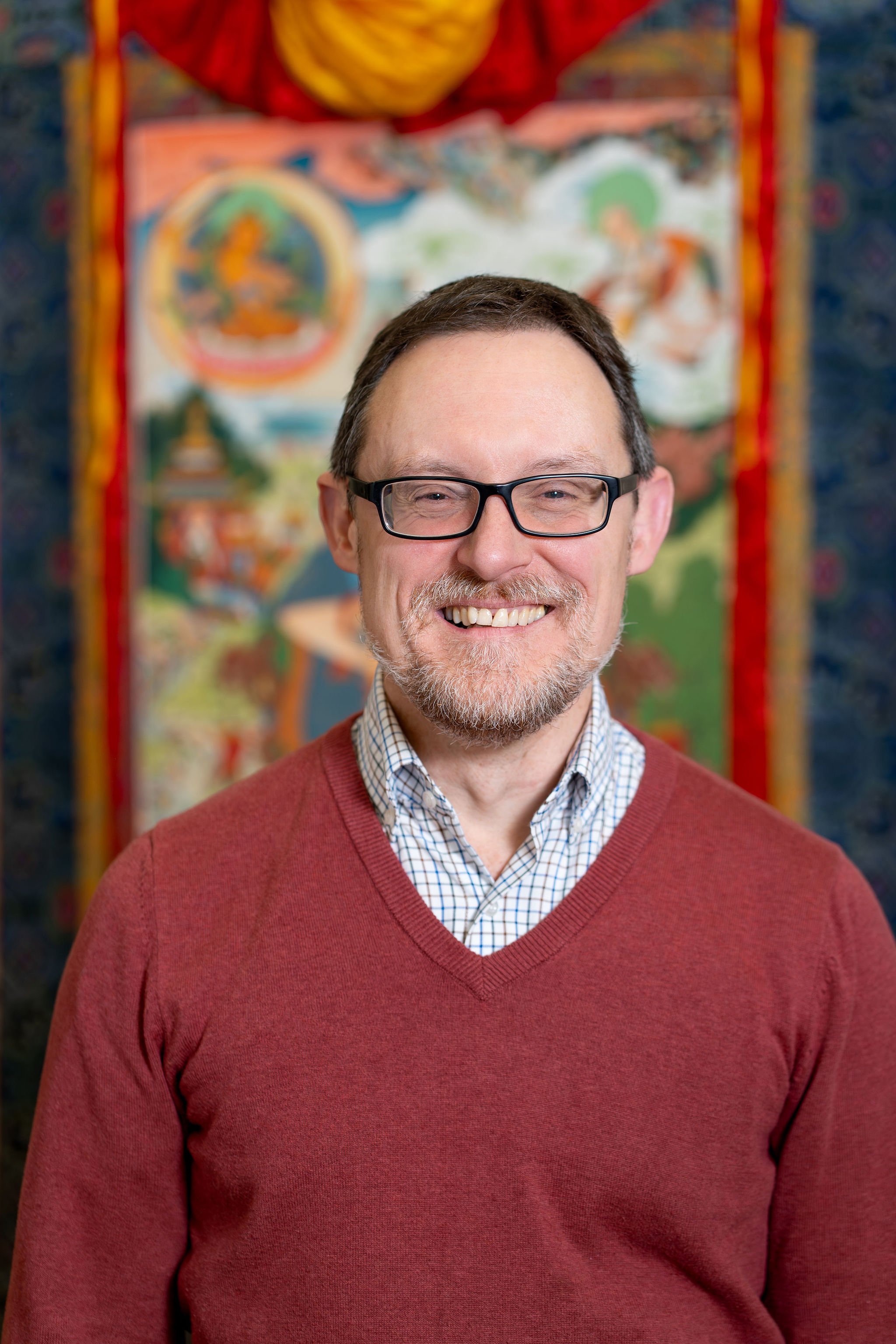 Man with glasses and striped shirt smiling