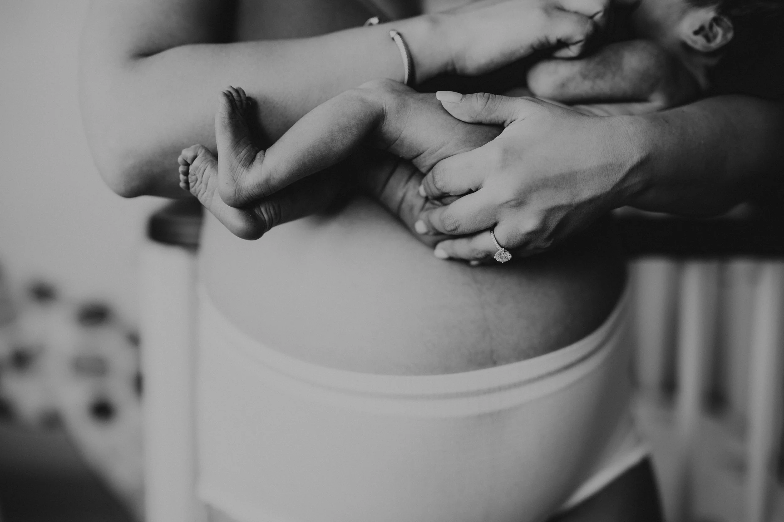 A pregnant woman is holding her brand new baby. Image is in Black and white