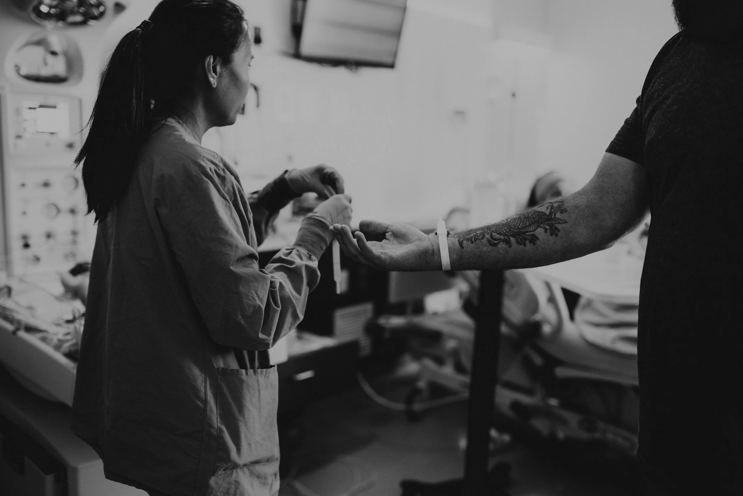 A nurse is putting a name bracelet on a new dad. 