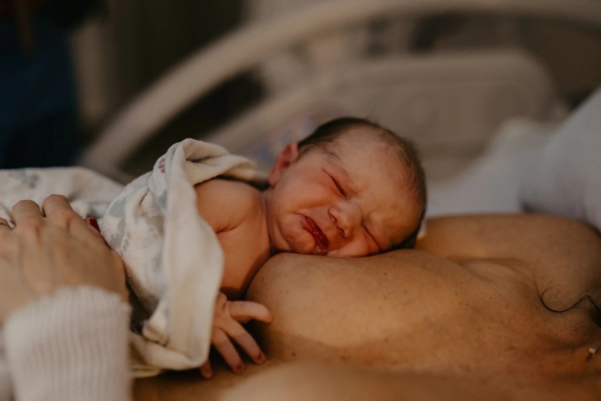 Newborn baby nursing on mother's breast.