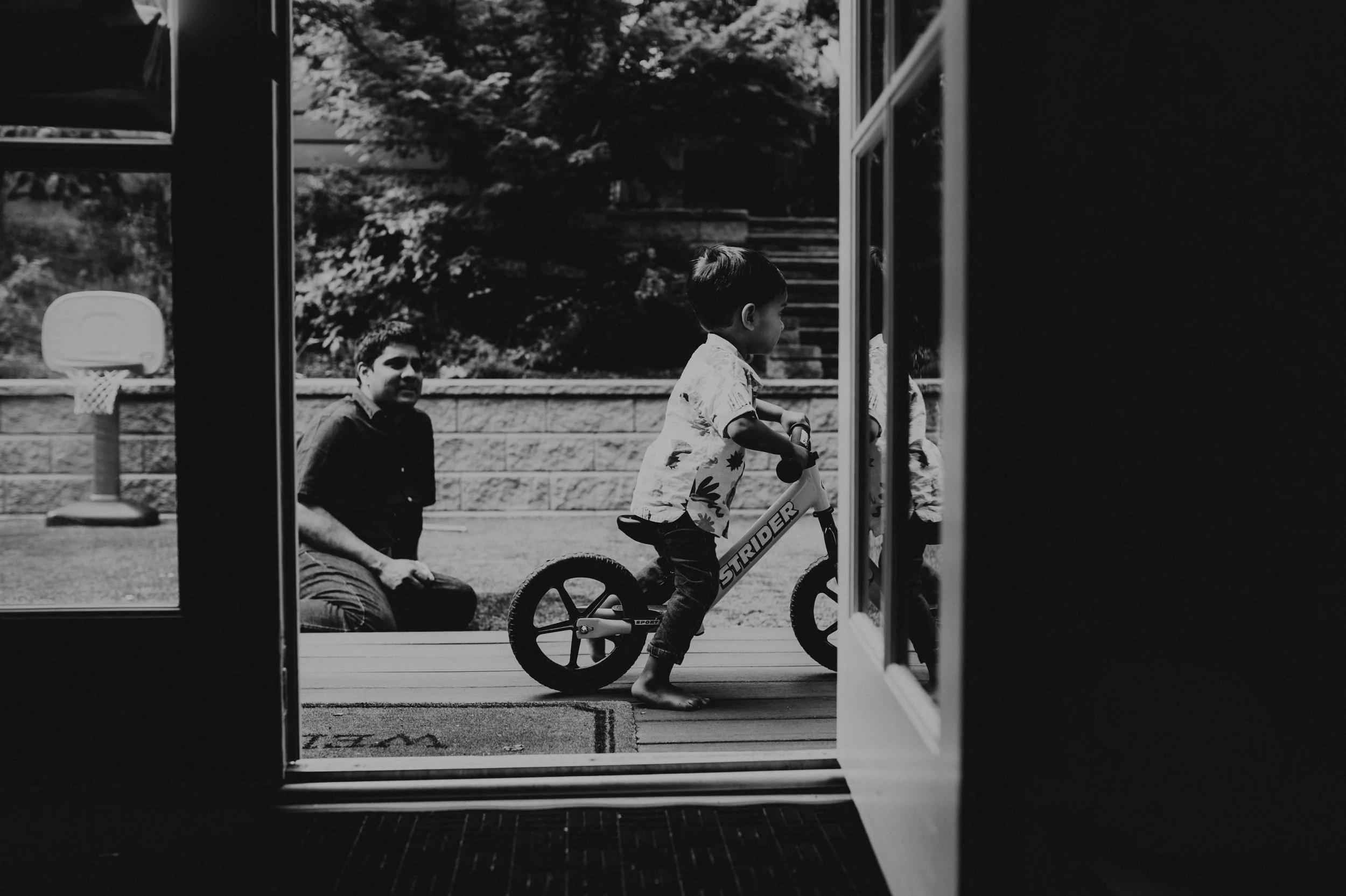 little boy learning to ride bike when dad is watching outside