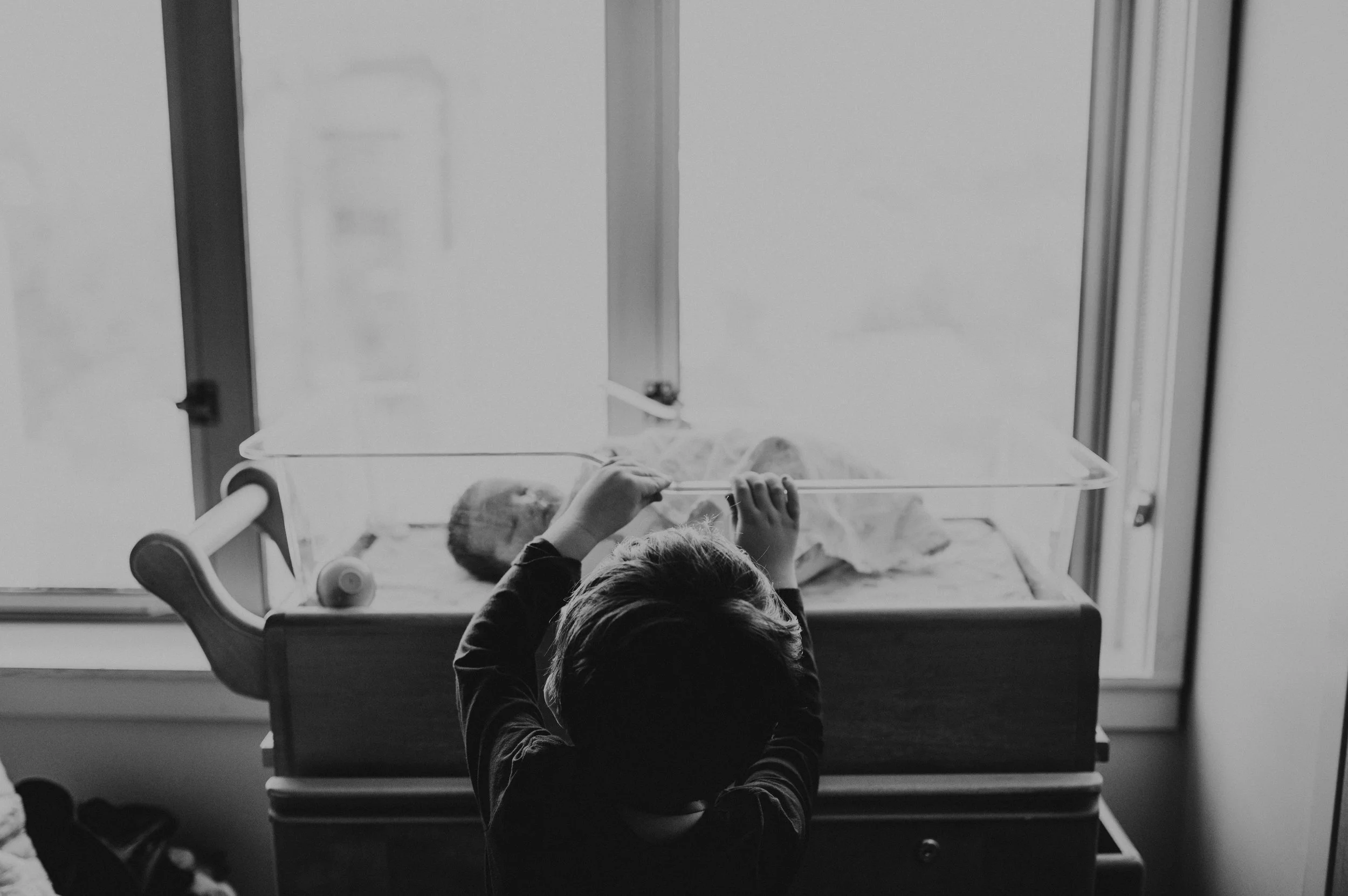 older sibling peeking in on newborn in hospital fresh 48 session 