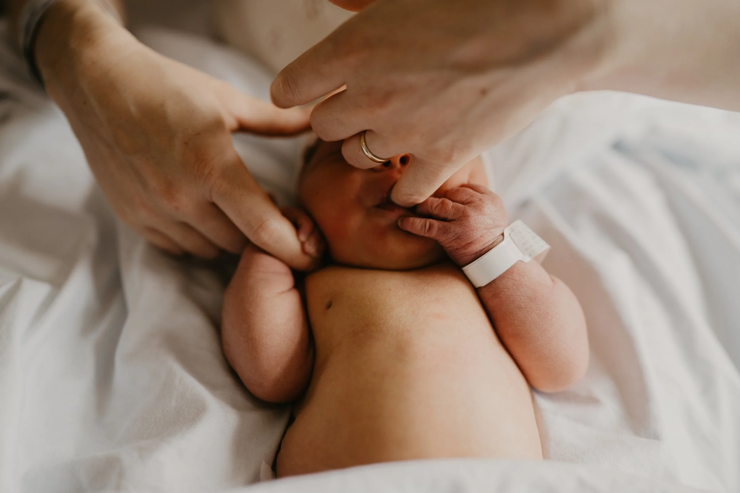 Close up of newborn baby's hand held by mother in hospital room at Swedish First Hill Seattle birth photography-Elizabeth Anderson Photography
