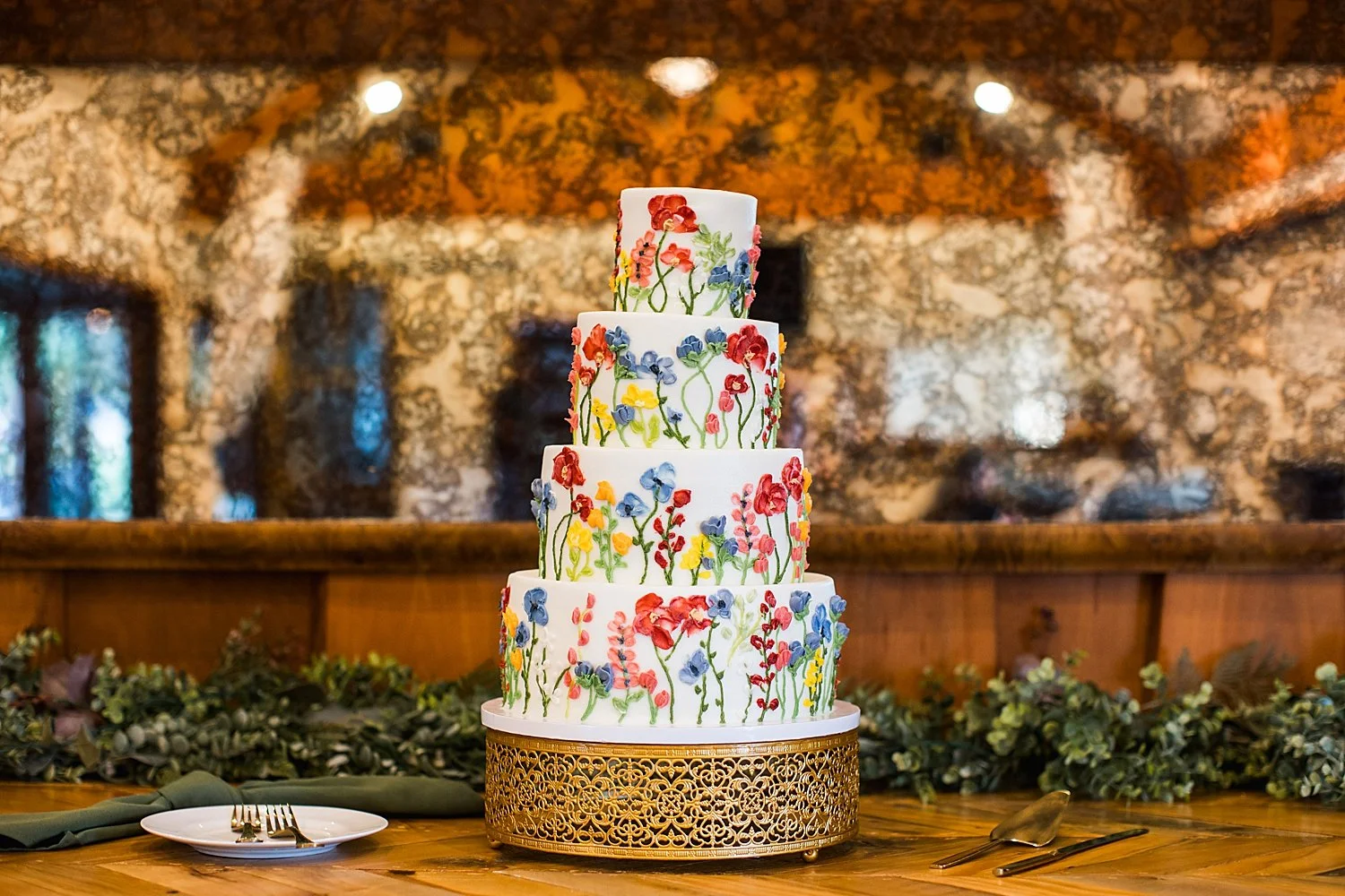 four-tier floral white cake on table by Shelley Elena Photography