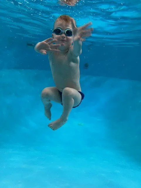Young boy swimming underwater wearing goggles.