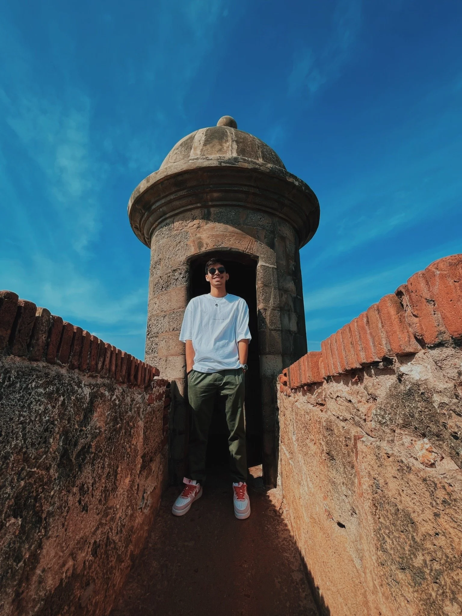 A person standing in a small guard tower on a historic fortress wall with a clear blue sky in the background.