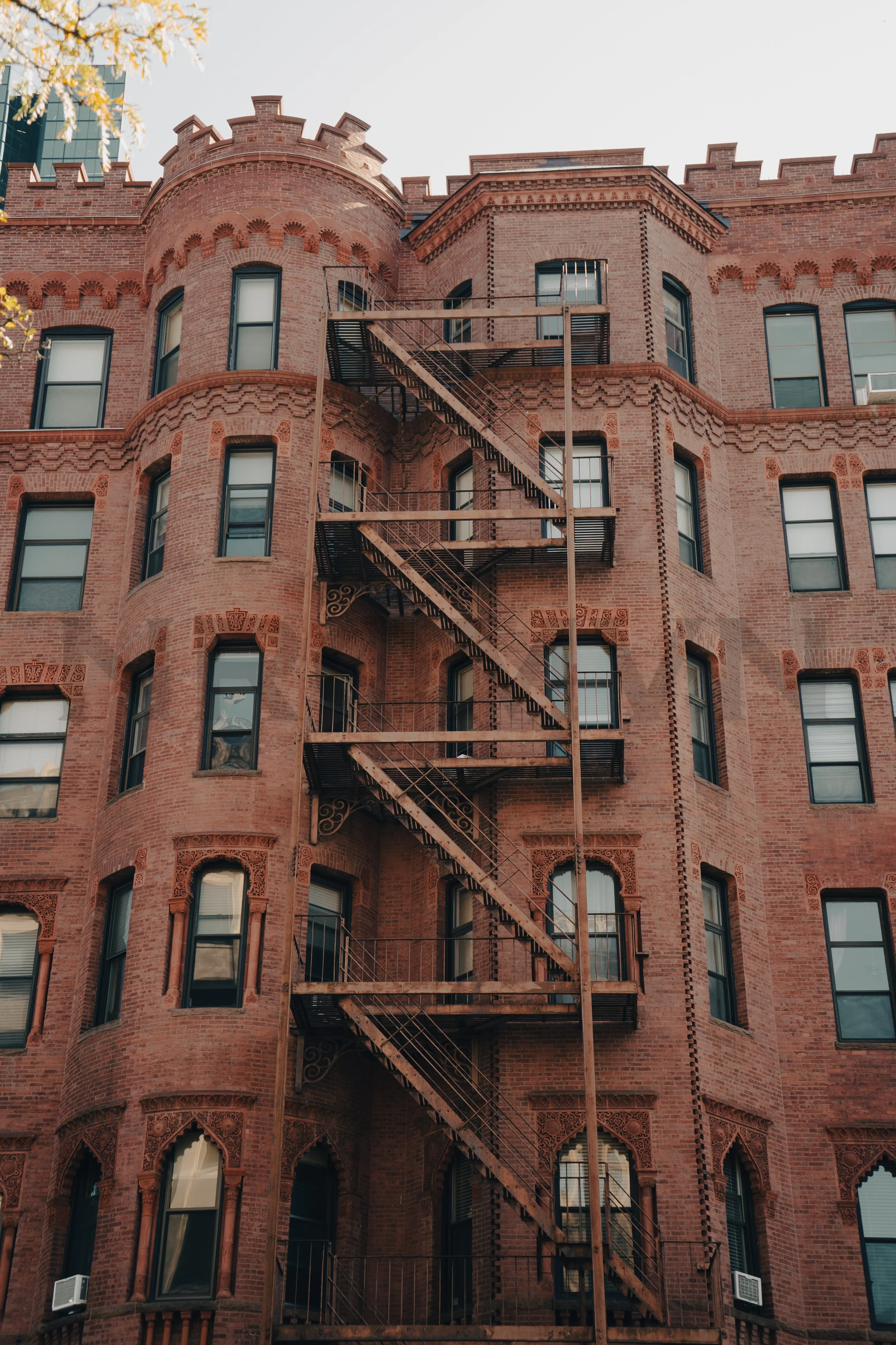 A multi-story red brick building with an external fire escape staircase running along its front facade.