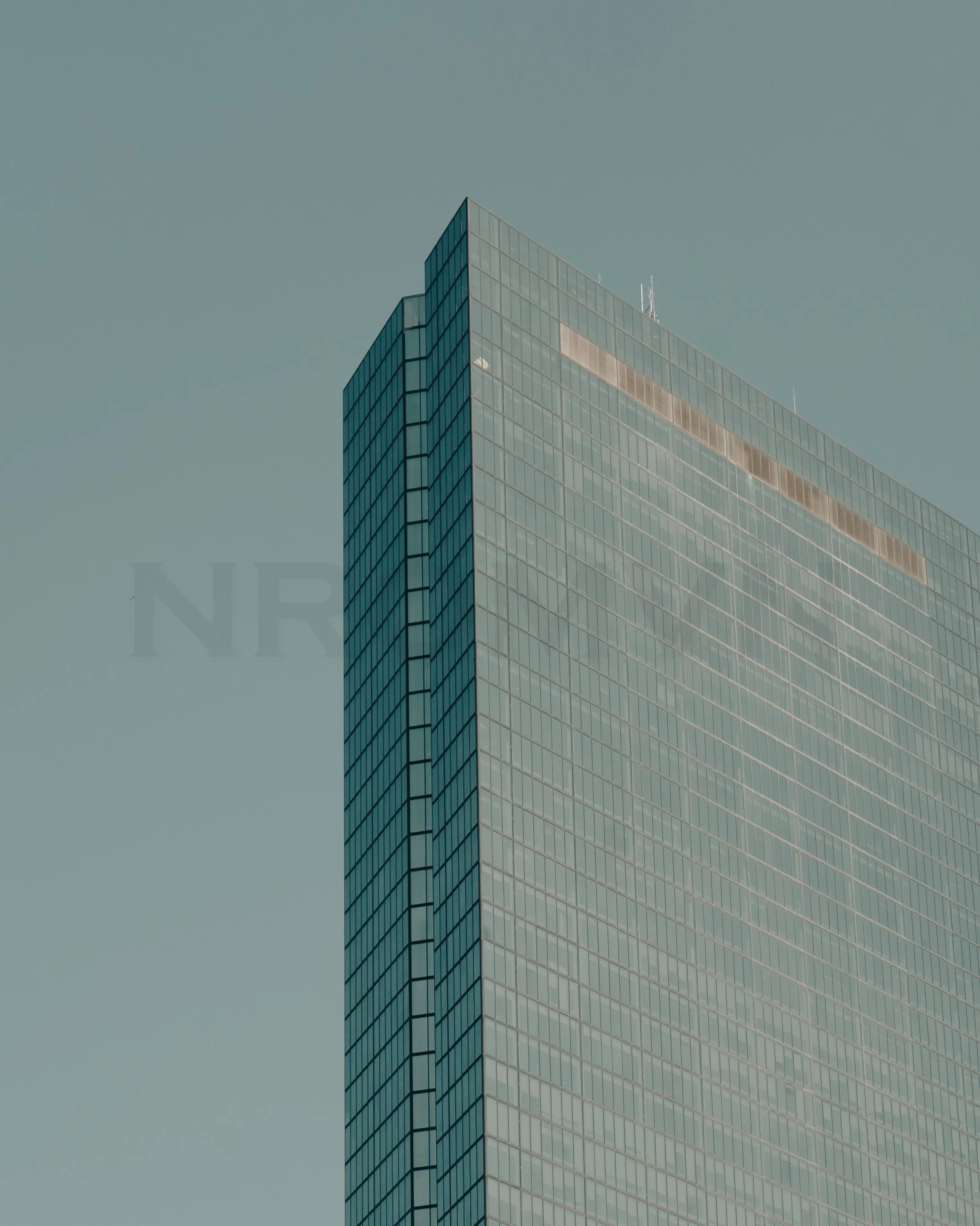 A tall modern glass skyscraper against a clear sky.