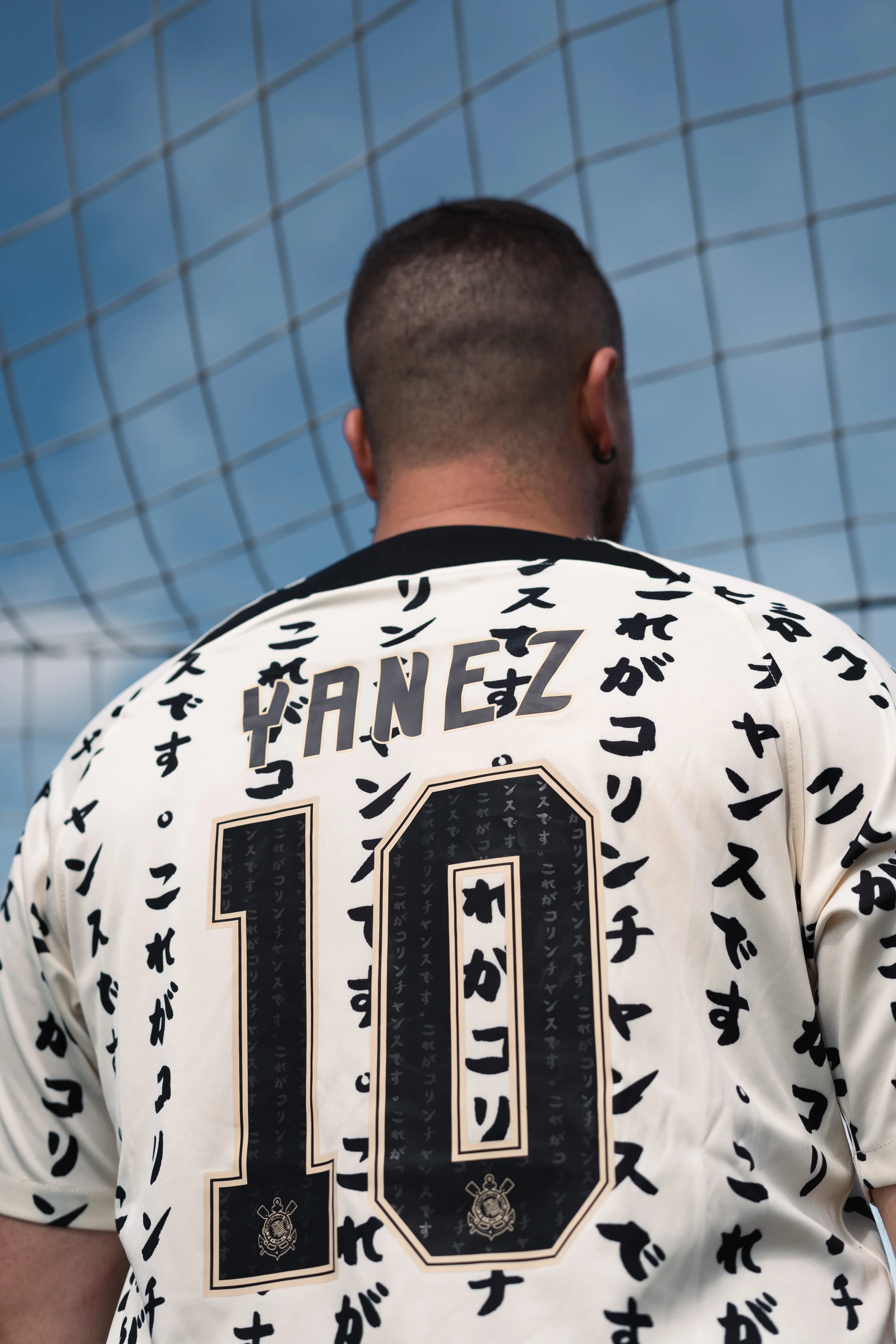 Back view of a person wearing a soccer jersey with the name 'YANEZ' and number '10', surrounded by Japanese characters, standing in front of a soccer net.
