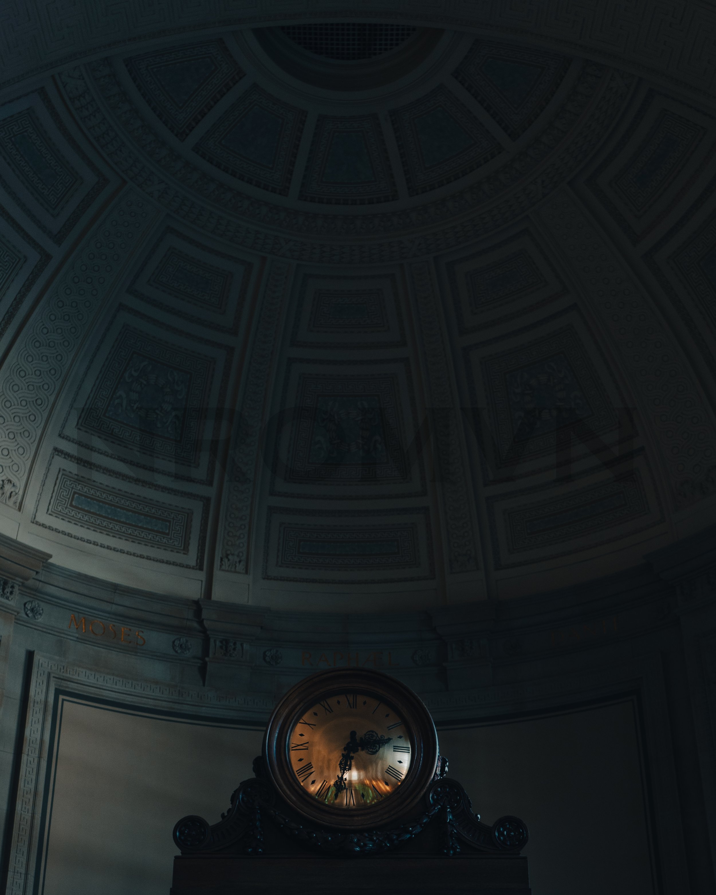 Grand interior with a domed ceiling and an ornate clock at the center, with names 'Moses' and 'Raphael' visible.