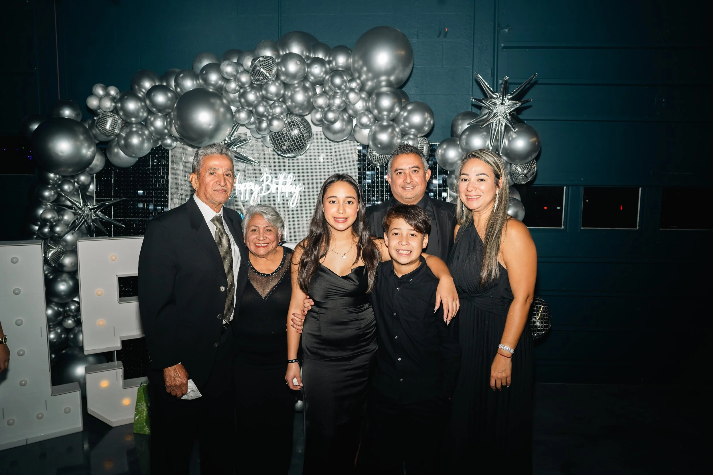 Family celebrating New Year's Eve with silver balloon decorations and a 