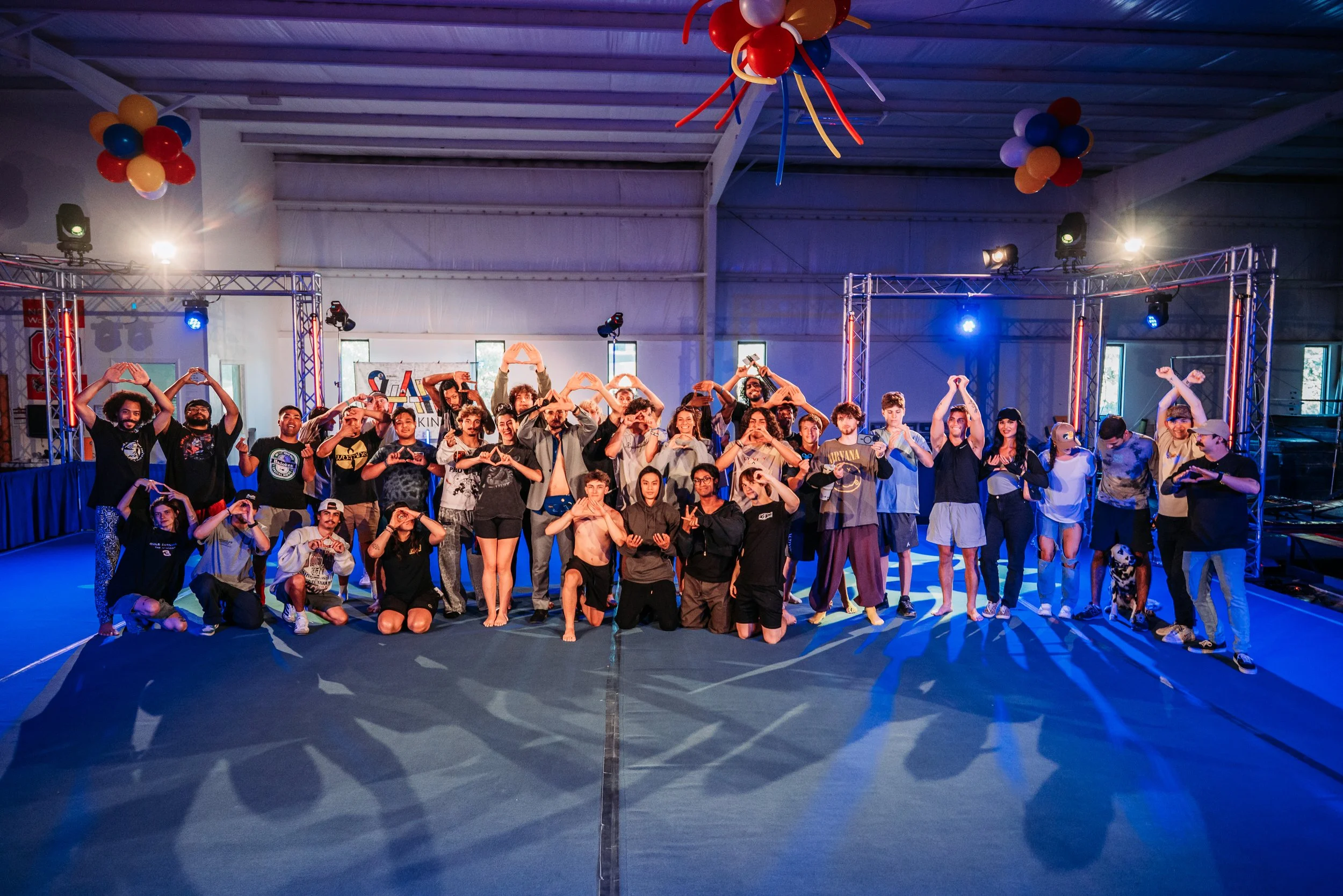 Group of people posing on a stage with colorful balloons and stage lighting in the background.