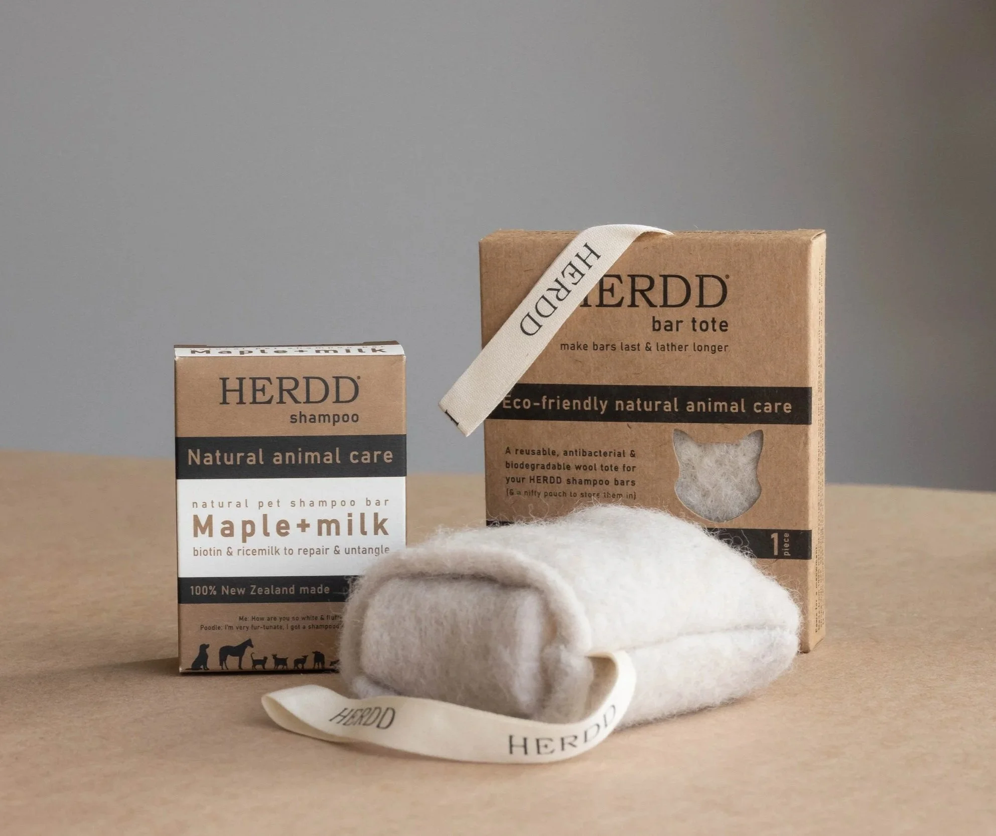 Two environmentally friendly pet care products: a bar shampoo labeled 'Maple + Milk' and a bar tote labeled 'HERDD', both made from natural, biodegradable materials against a plain background.