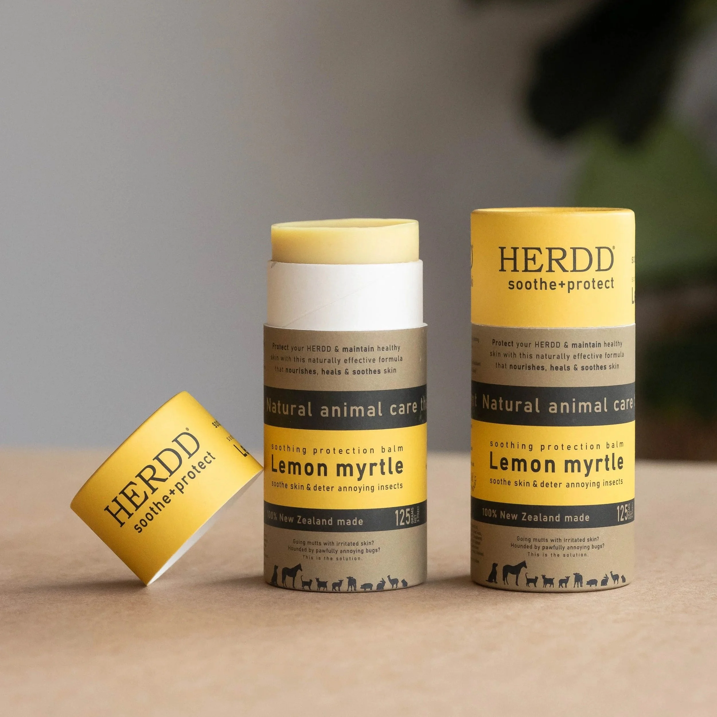Three bottles of HERDD soothing protection balm, with one bottle lying on its side. The labels on the bottles indicate they are natural animal care products from New Zealand, designed to soothe skin and deter insects.