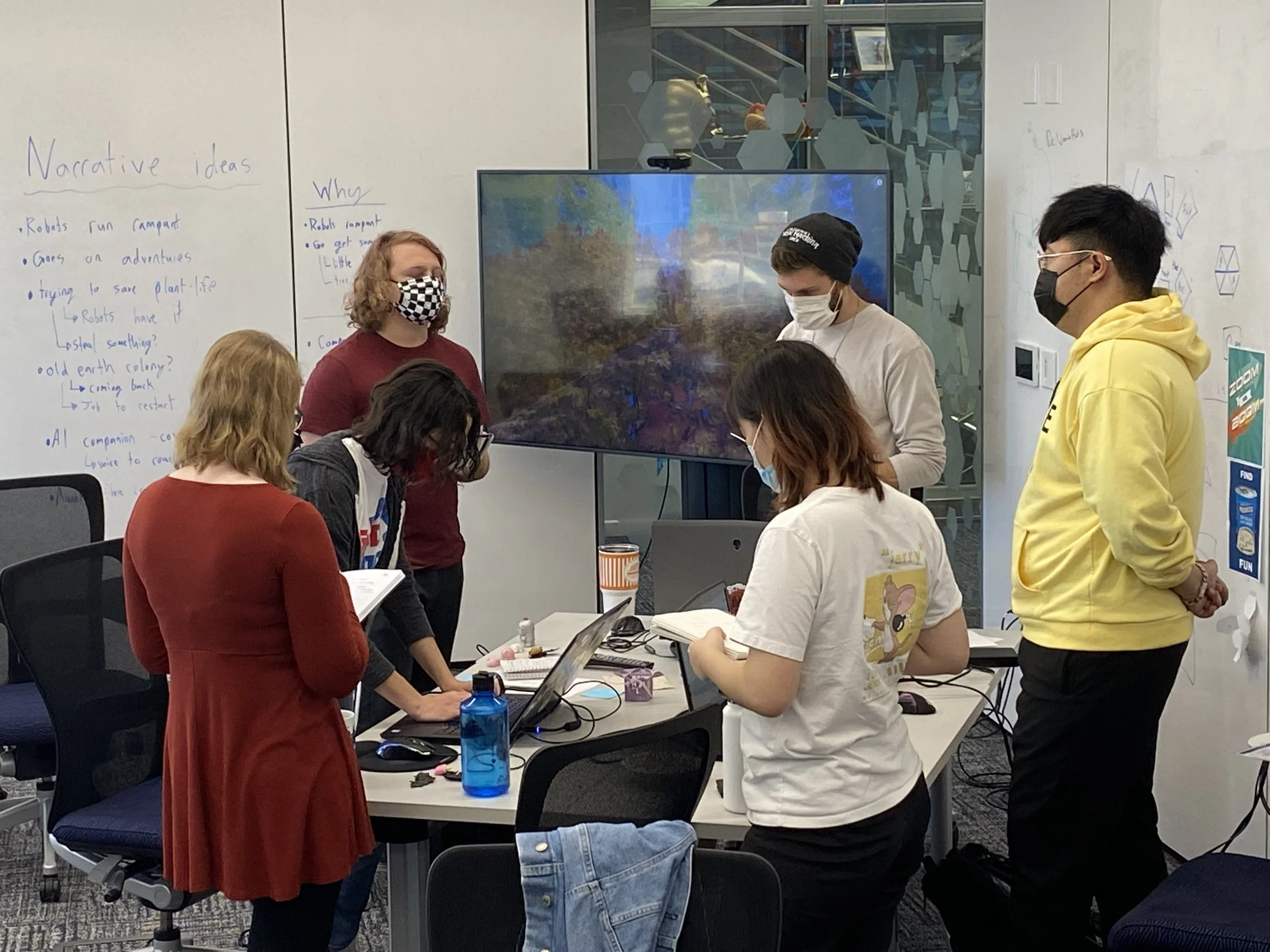 Photo of the leads table during morning scrums. The leads stand together, reading off their notes.