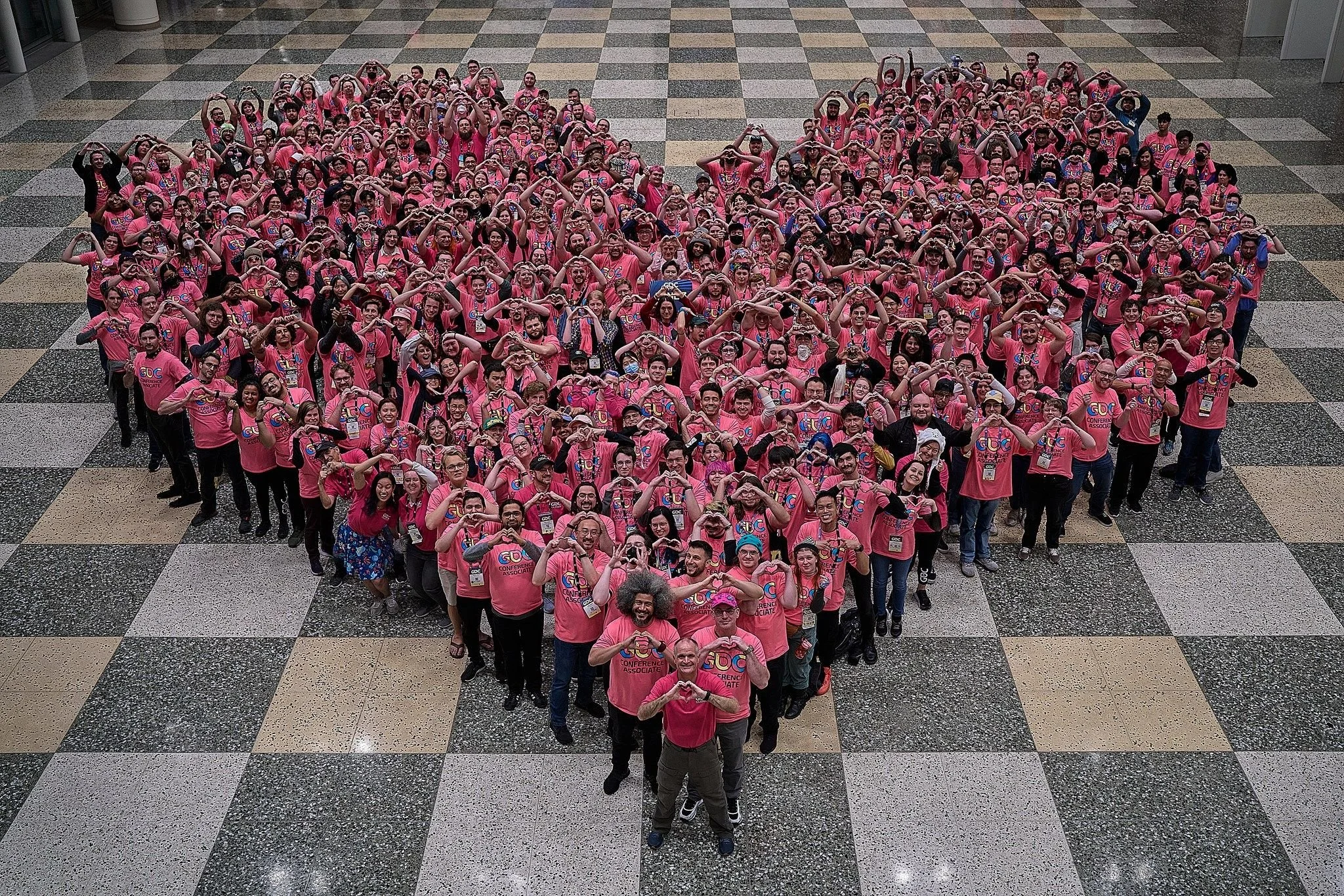 A photo of a group of peope standing in the shape of a heart.