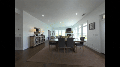Spacious modern dining and living room with large windows, wooden flooring, and neutral decor.