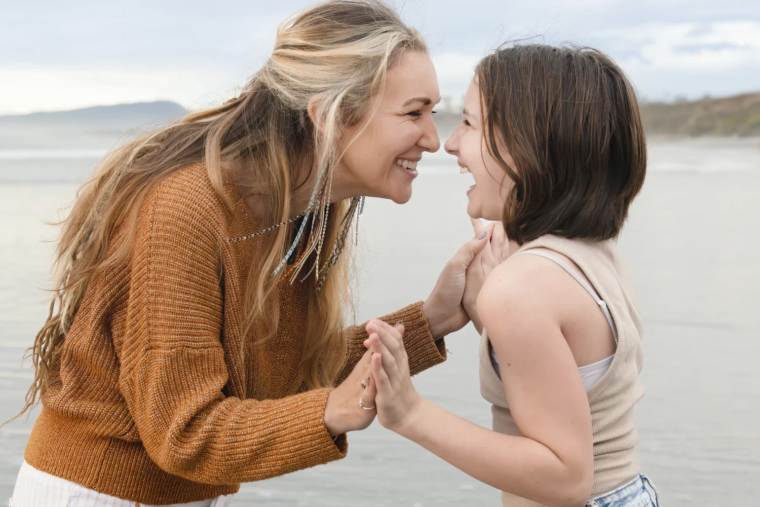 A mother and daughter laughing and holding hands.