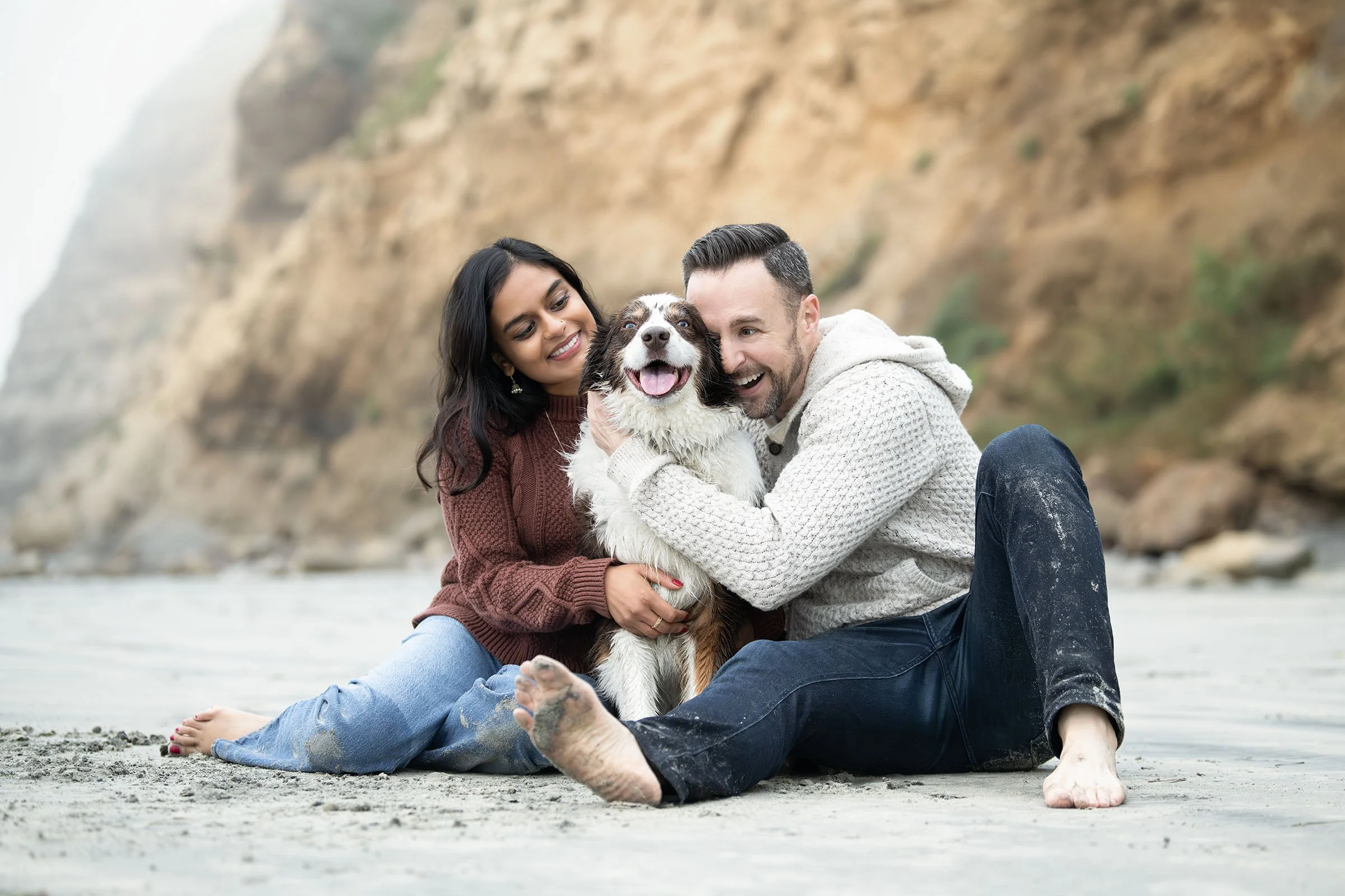 A couple and their very happy Australian Shepherd at the beach.