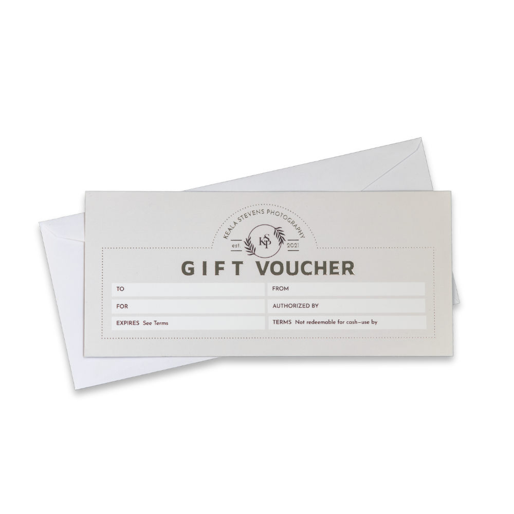 White gift voucher with black text and logo, partially placed inside a white envelope, on a black background.