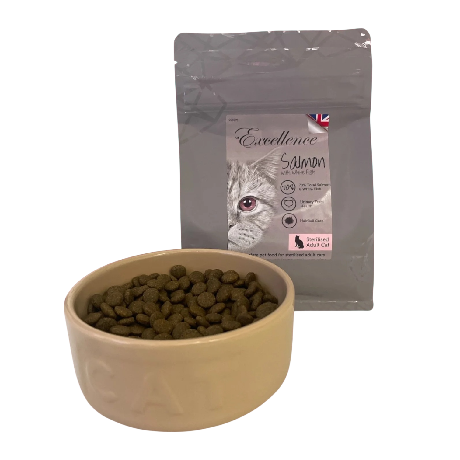 A bowl of dry cat food placed in front of a bag of Excellence salmon cat food, which features an illustration of a cat's face and a pink label indicating it is for sterilized adult cats.