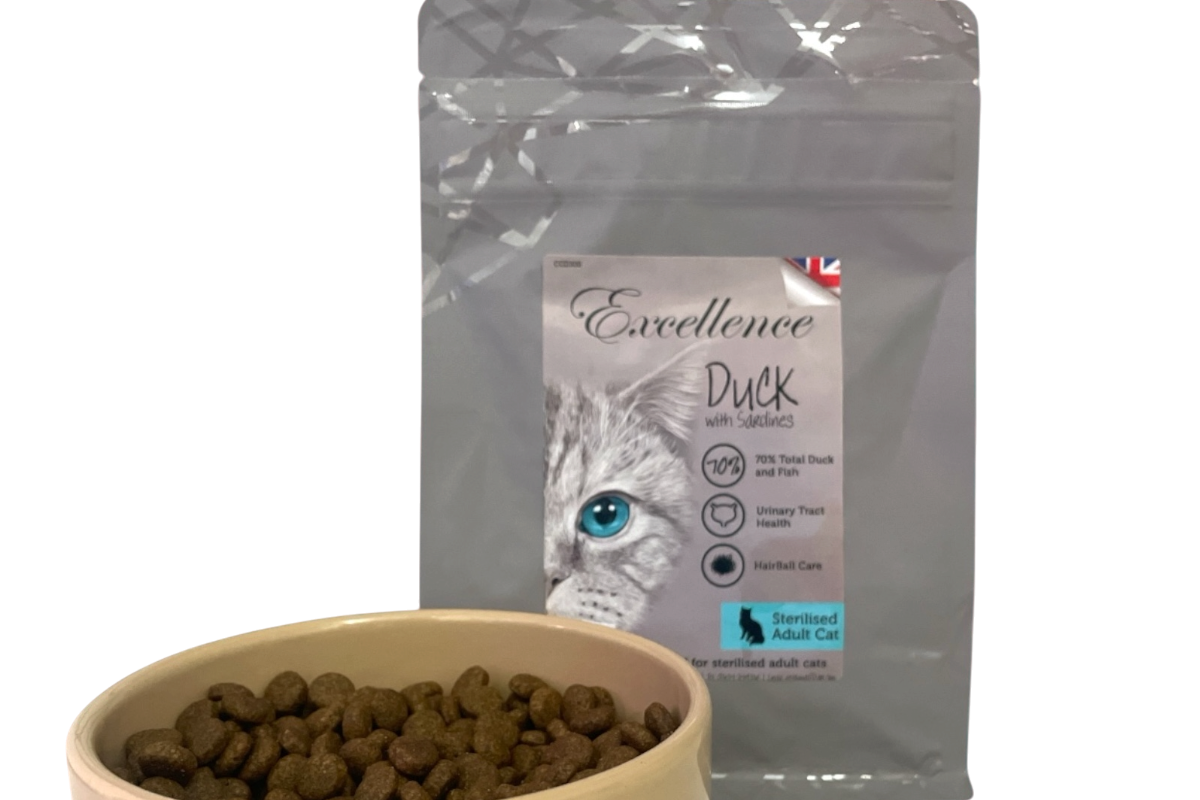 Bag of Excellence Duck cat food with sardines next to a bowl filled with dry cat food pellets.