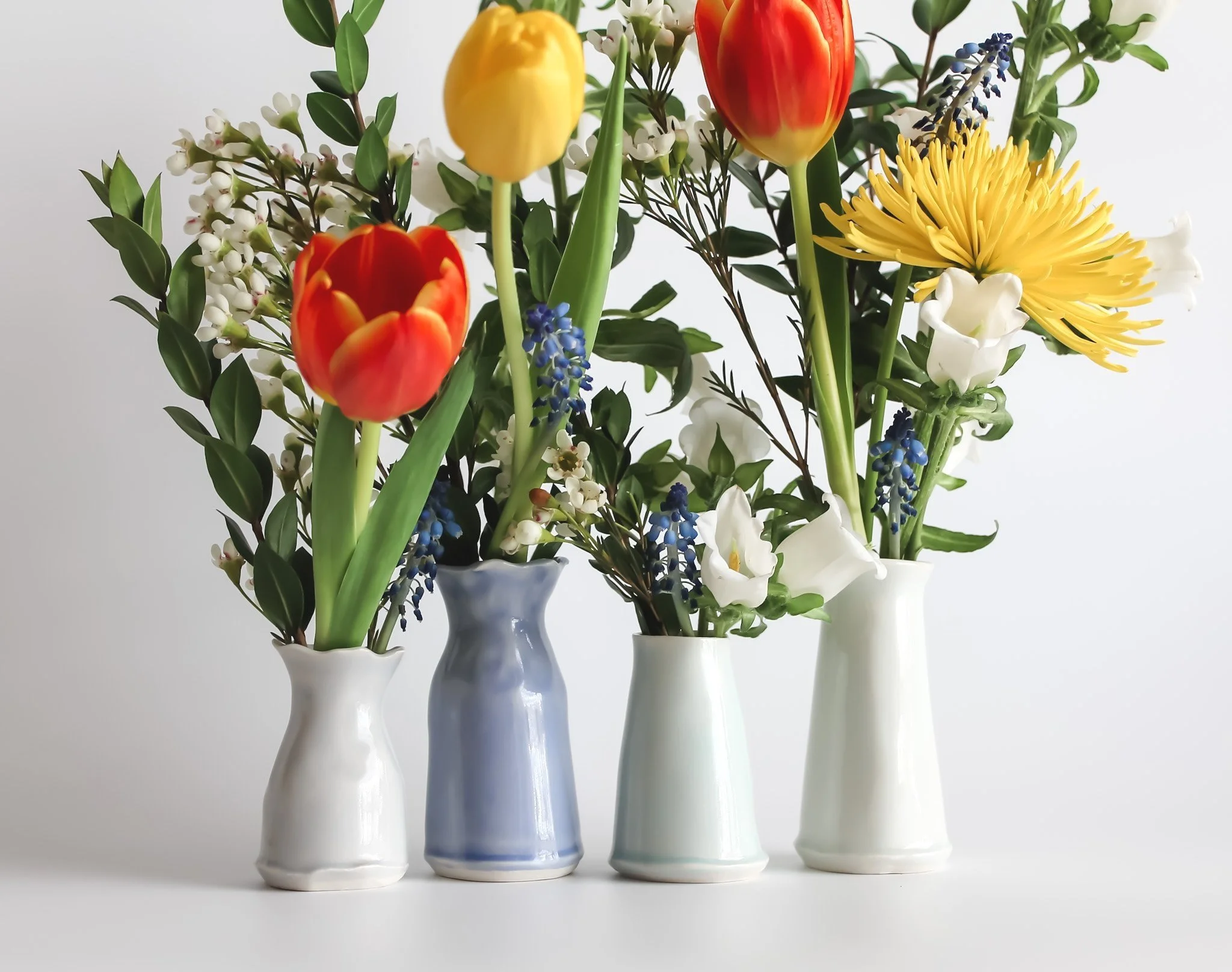 Hand built bud vases with flowers in them