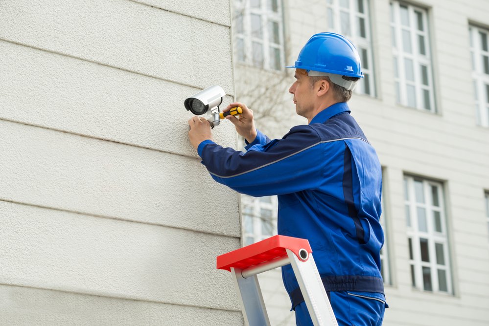 Técnico instalando una cámara de videovigilancia en una pared