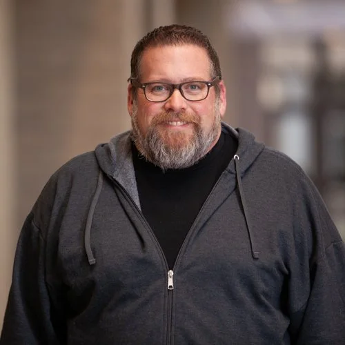 Man with glasses and beard wearing a dark hoodie
