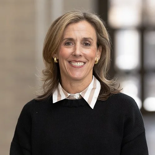 Woman smiling wearing a black sweater with a white collared shirt