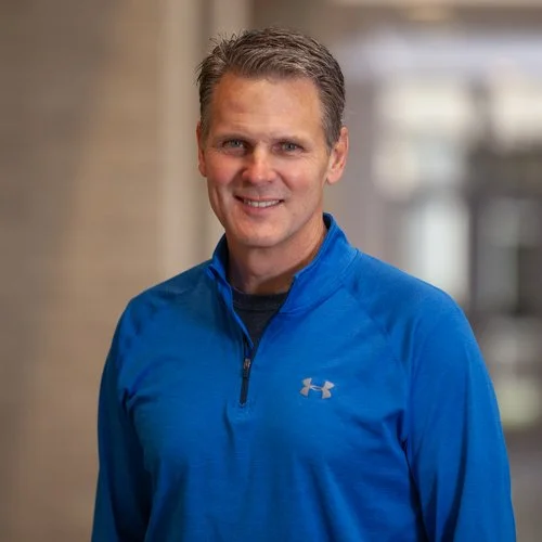 Man wearing a blue Under Armour shirt with a neutral expression indoors.
