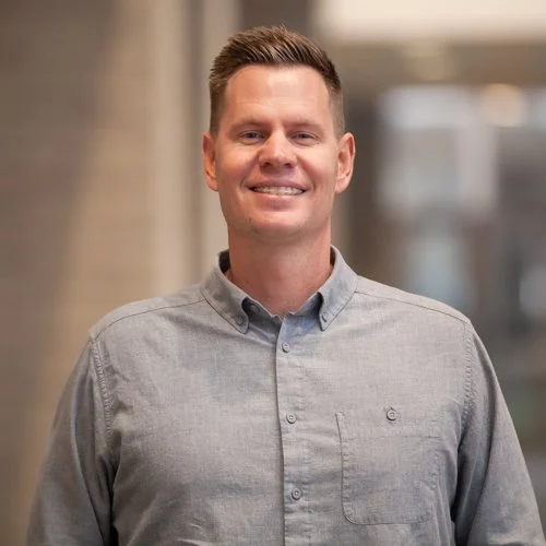 Smiling man in a button-up shirt, neutral background