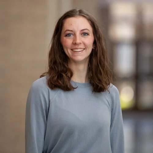 Woman with long brown hair in light blue sweater smiling