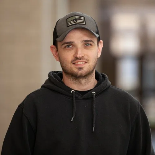 Man wearing a cap and hoodie standing outdoors