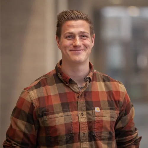 Man wearing a plaid shirt standing and smiling indoors