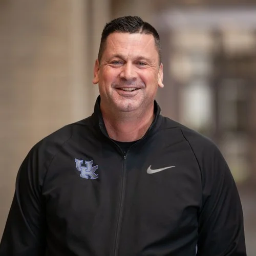 Smiling man wearing a black jacket with UK logo and Nike swoosh