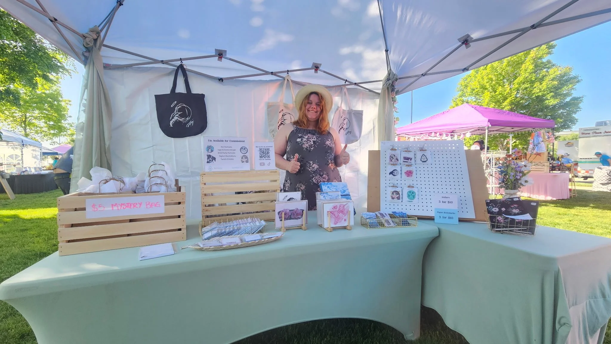 Korina at a koriejoy market booth outside in a tent with products displayed on tables