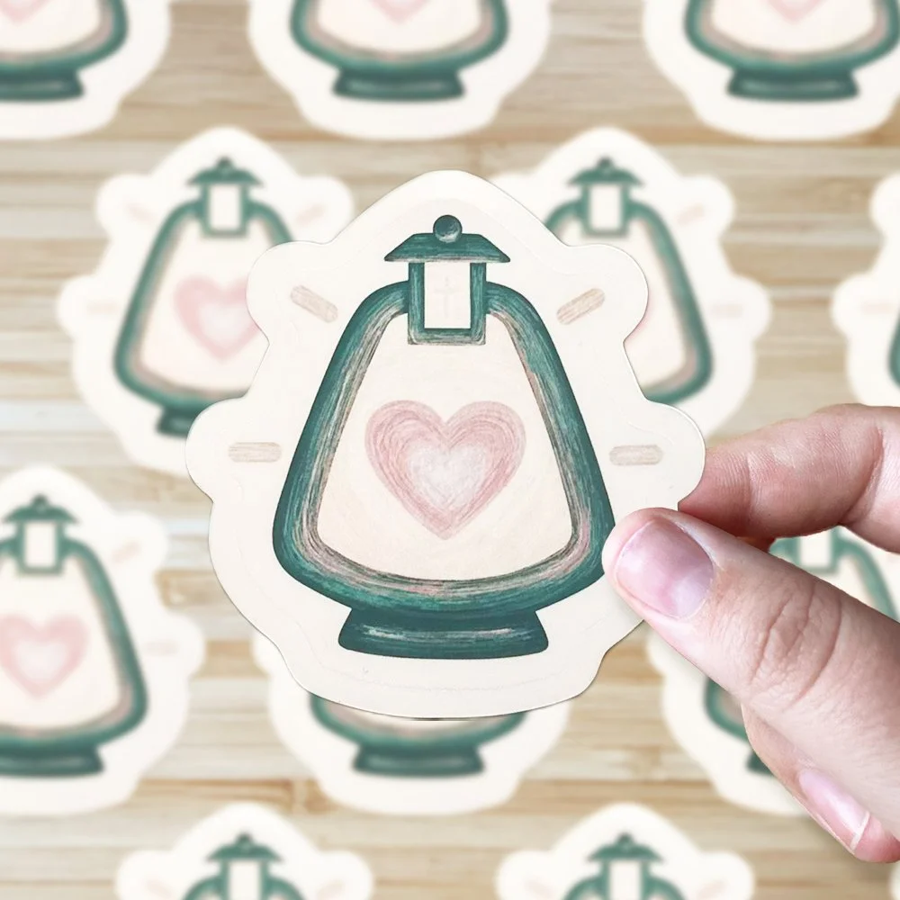 Hand holding a sticker of a green lantern with a pink heart inside