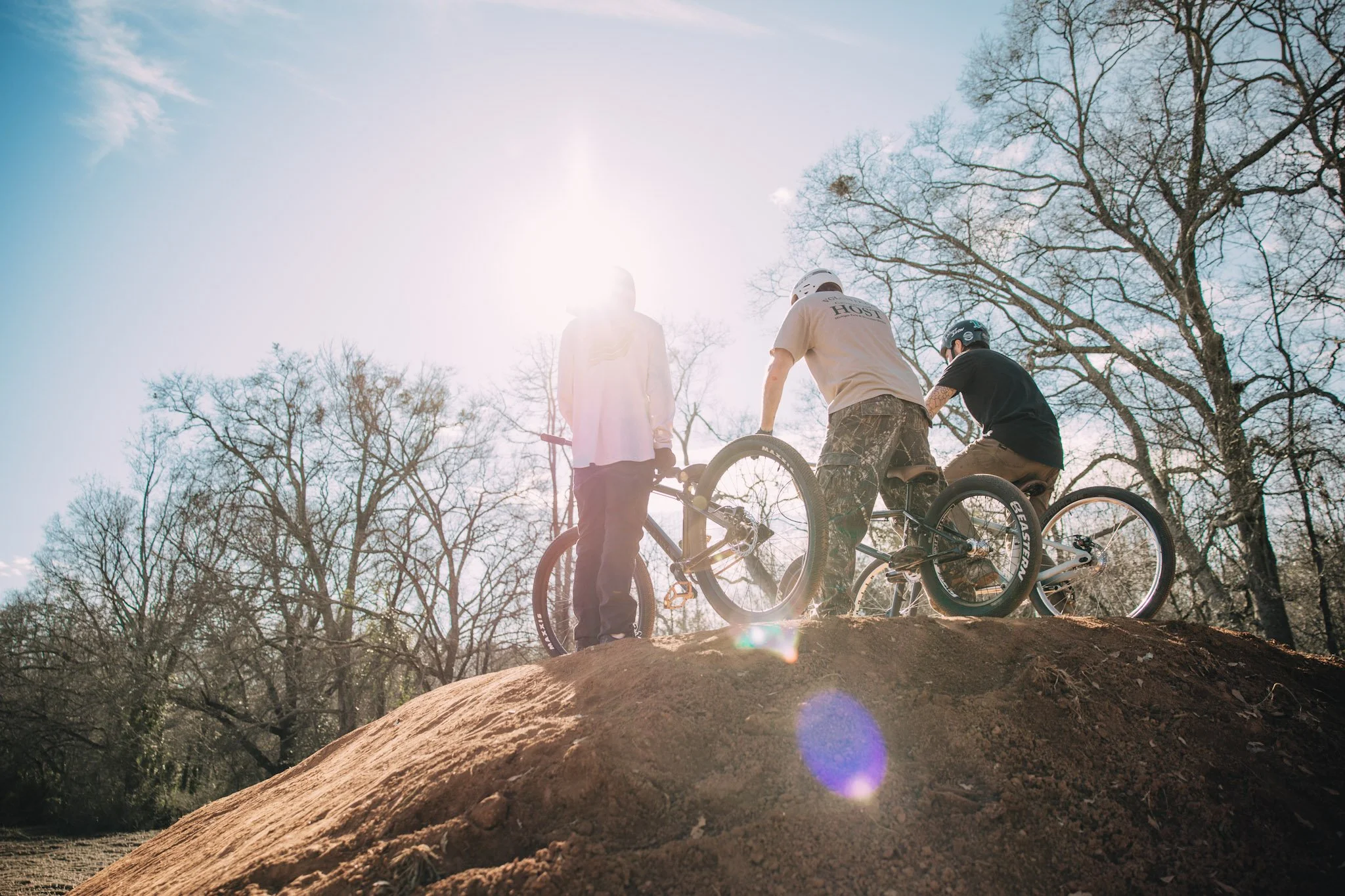 A person performing a backflip on a BMX bike at an outdoor skate park during sunset.