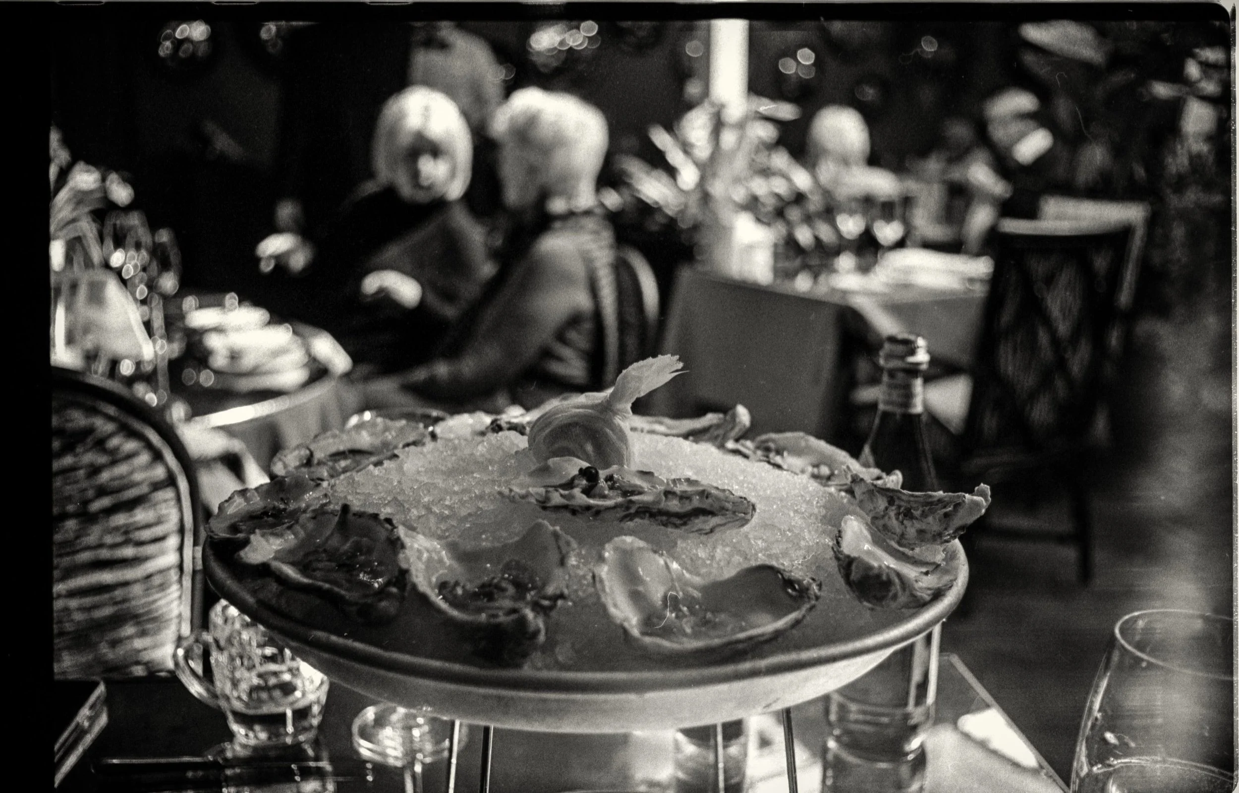 Plate of food on a glass table with a restaurant setting in the background, blurry.