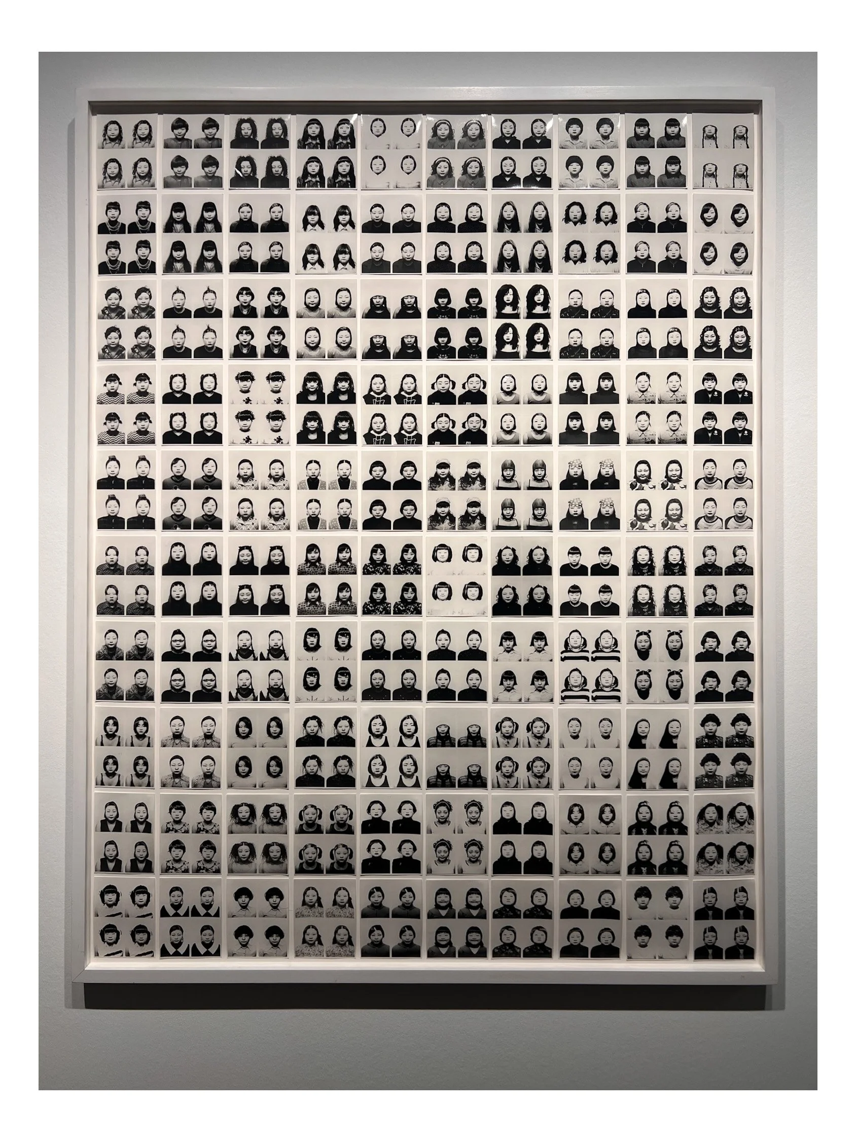 A framed collage of black-and-white portrait photographs of children arranged in a grid.