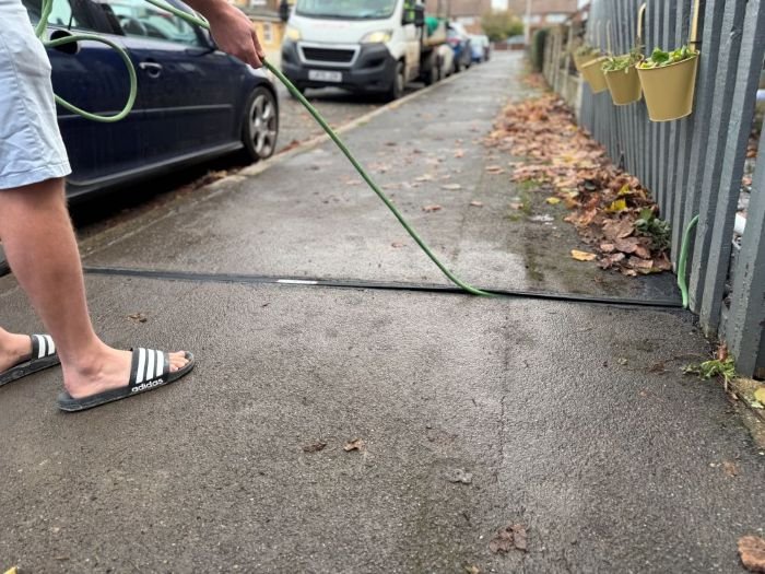 Man in flip flops extracting an EV cable from a cable gully in the pavement
