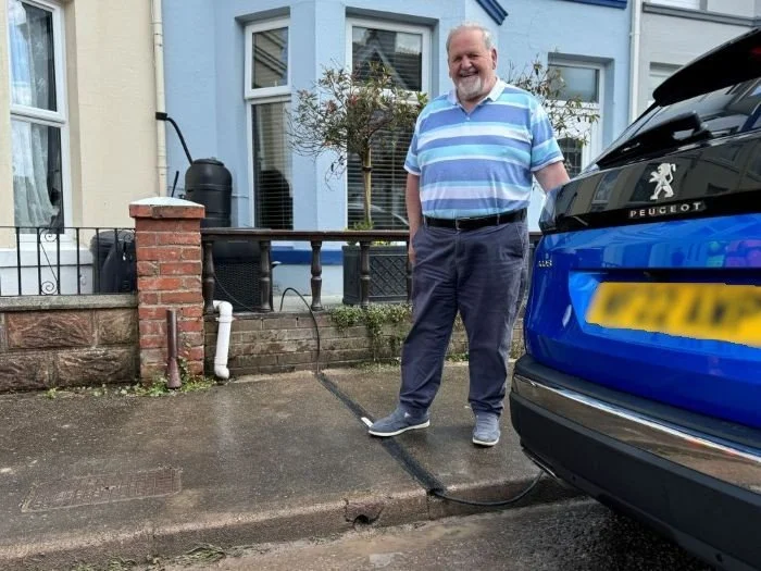 Kerbo Charge customer stood next to EV cable gully and car on Devon street