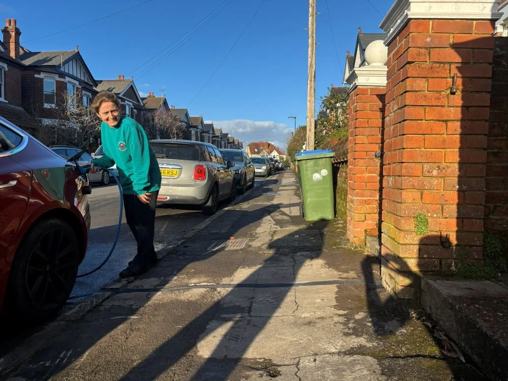 lady charging car at kerbside using ev cable channel