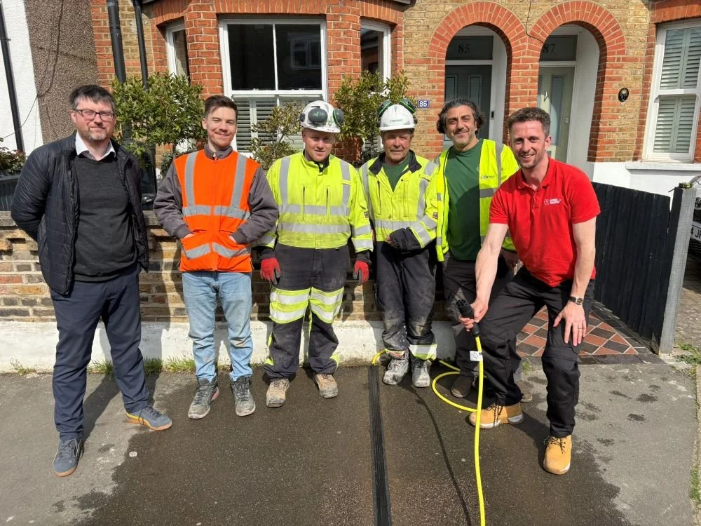 6 men, some in hi vis, stood next to a newly installed EV cable gully in the pavement