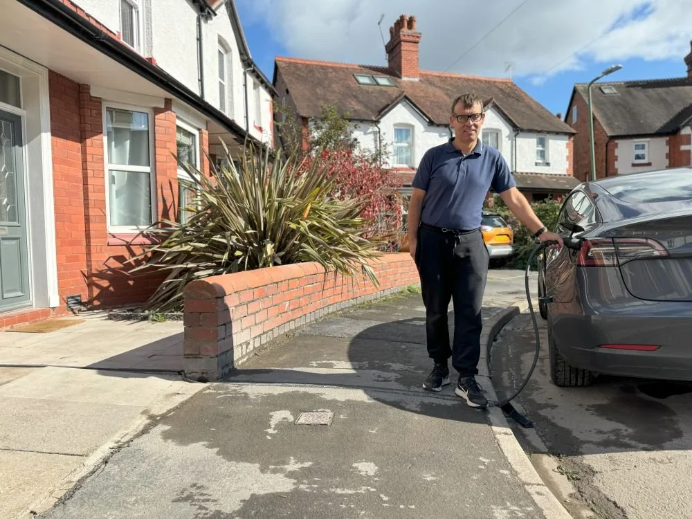 Man charging car using newly installed EV cable gully in pavement