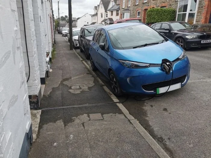 Blue EV being charged outside terraced house in Cornwall