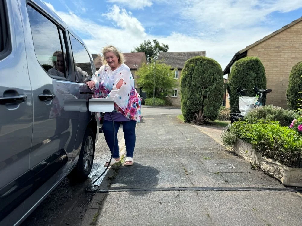 Woman charging grey Electric Van parked on the street